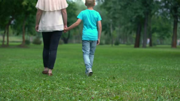 Mother and Son Holding Hands, Walking Away Together, Concept of Child Adoption