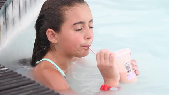 Young Girl Relaxing Sipping Fruit Juice in a Natural Pool