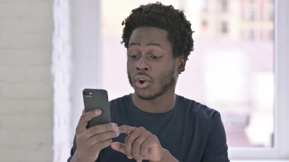 Portrait of Cheerful Young African American Man Using Smartphone