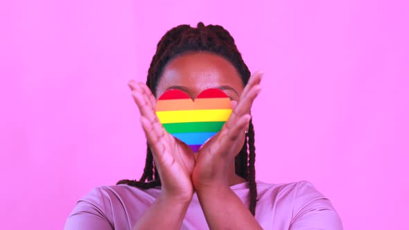 Afro American Woman Holding a Heart Shape in Pink Studio Background