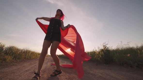 Woman with Pieces of Red Cloth Dance Near the Field with Wind Generators 