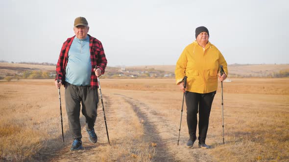 Seniors Couple Nordic Walking in Autumn Forest.