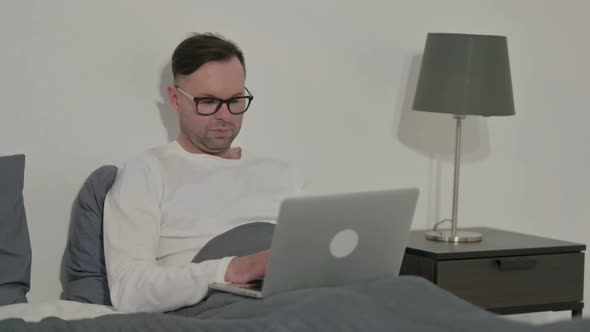 Casual Man Working on Laptop in Bed