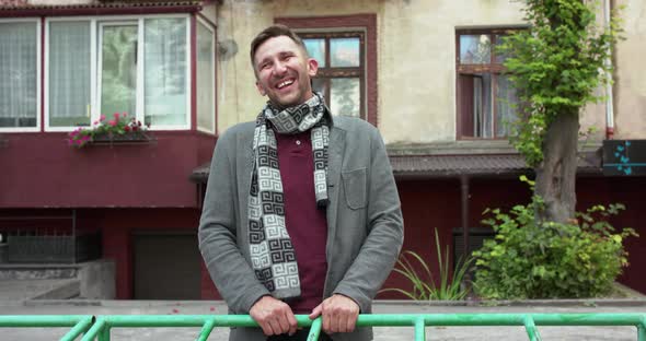 Portrait of Charismatic Man Laughing at Camera and Leans on Crossbar on the Yard