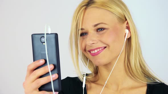 A Young Attractive Woman Listens To Music on a Smartphone - Closeup - White Screen Studio