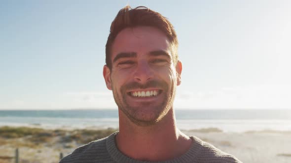 Happy caucasian man standing and smiling by the sea