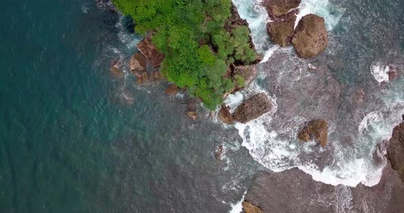 Aerial top down shot of crashing water against rocks and boulders near Jungwok Beach,Indonesia