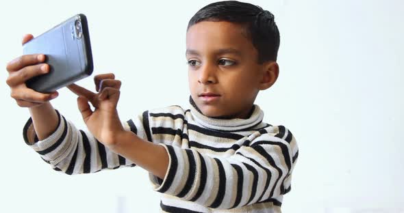 one Pakistani kid holding a mobile phone and taking some selfies