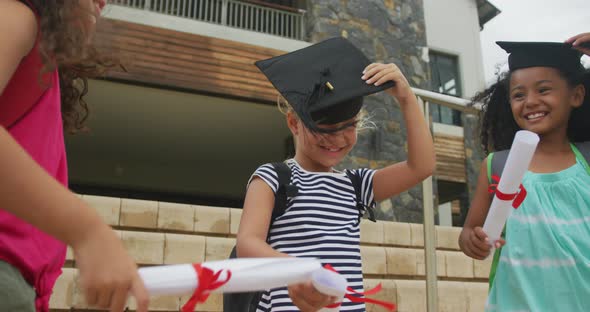 Video of happy diverse girls tossing hats after graduation