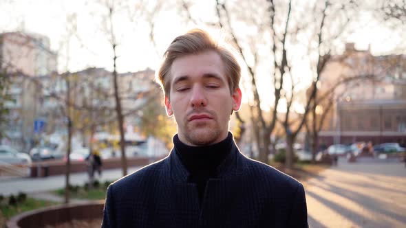 Portrait of Handsome Tired Man Looking at Camera an Sunset Urban Background