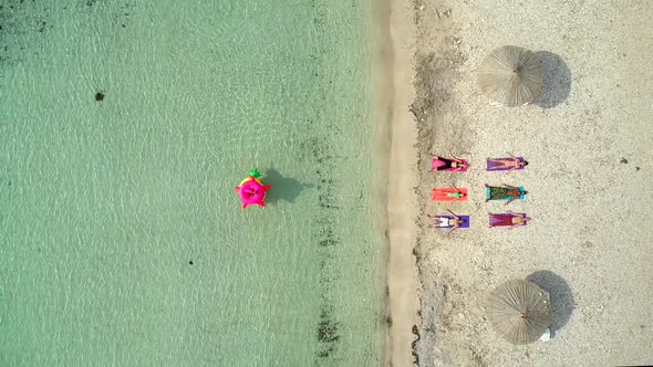 Aerial view of people lying in yoga pose on on the with inflatables.