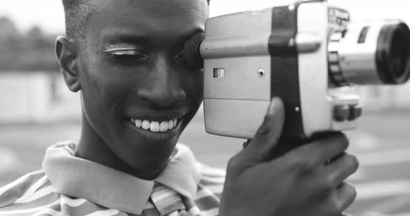 Young african man using vintage old video camera outdoor