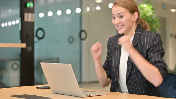 Beautiful Young Businesswoman Celebrating Success on Laptop in Office