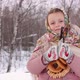 Cute girl in a traditional Russian headscarf and mittens playing on spoons on winter forest backgrou - VideoHive Item for Sale