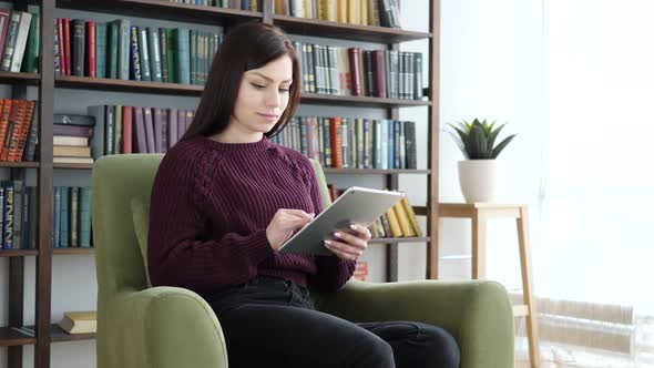 Woman Sitting on Casual Chair Browsing Internet on Tablet