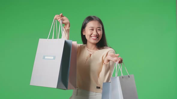 Asian Shopping Woman With Shopping Bags Smile To Camera While Standing In Front Of Green Screen