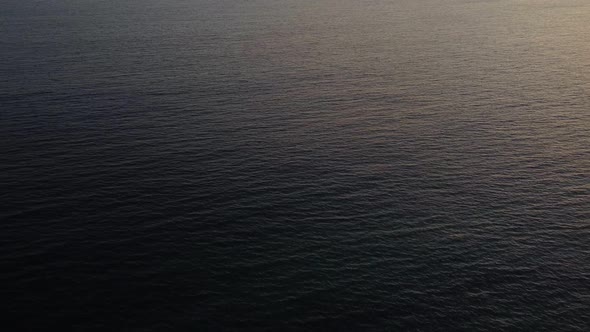 Arial shot of an ocean surface in sunset.