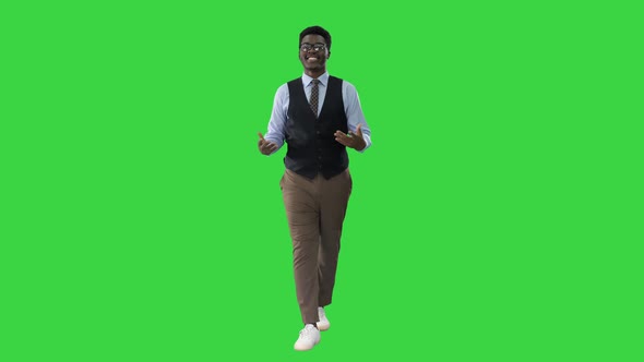 Young African American Businessman Gesturing and Talking To Camera While Walking on a Green Screen