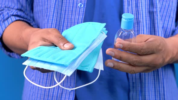  Man Hand Holding Surgical Face Mask and Sanitizer Gel 