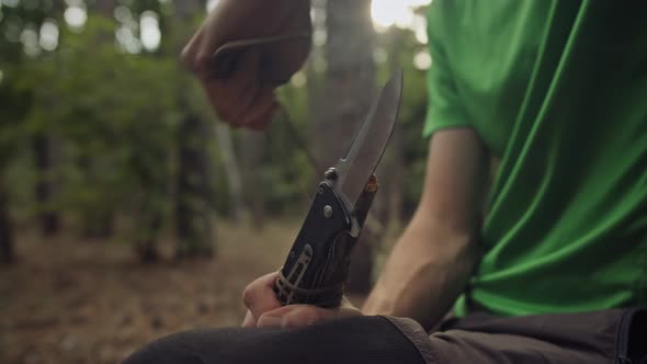 A Male Survivalist Ties a Knife with a Rope to a Stick