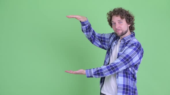 Happy Young Bearded Hipster Man Snapping Fingers and Showing Something