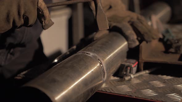 Welder breaking off any excess weld flux with hammer