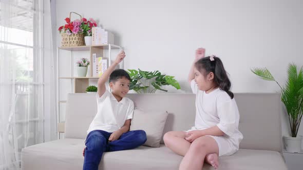 2 kids sitting and playing rock paper scissors game together with happy and laughing