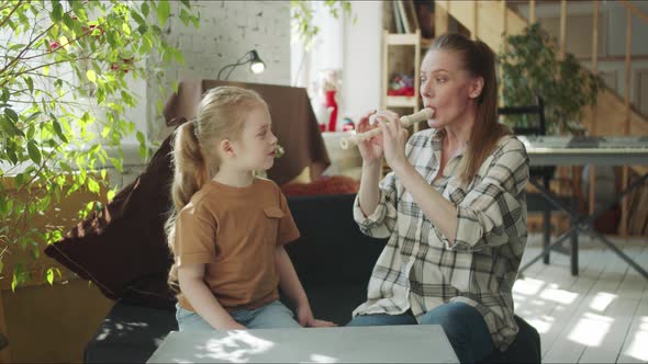 The Girl Watches Her Mother Play the Flute Laughs and Covers Her Ears