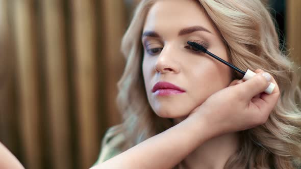 Hands of Professional Makeup Artist Applying Mascara on Eyelashes of Model
