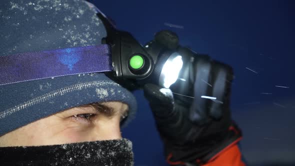 Close Shot of Man in Snow Gear Adjusting Headlamp