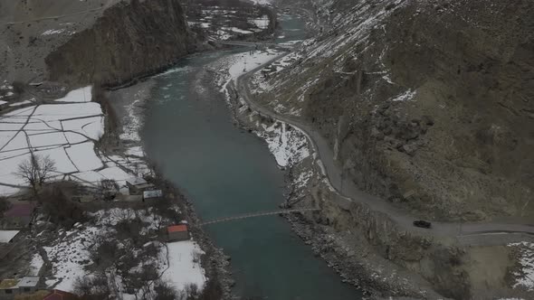 Aerial Drone Surveillance Footage Of Black Car Approach Bend Beside River In Hunza Valley. Dolly Zoo