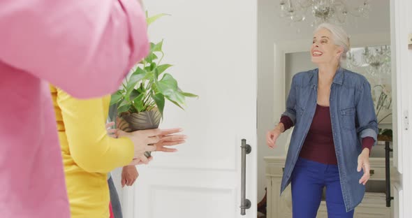 Animation of happy caucasian senior woman welcoming friends in doorway
