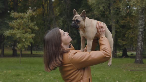 Woman Looking at Her French Bulldog That Holding in Hands