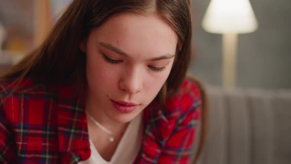 Young Woman in Red Checkered Shirt Looks Down in Living Room