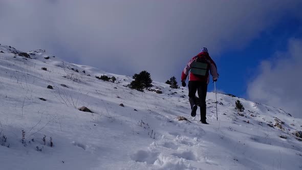 Climber Reaches the Top of Snowy Mountain on Sunny Winter Day