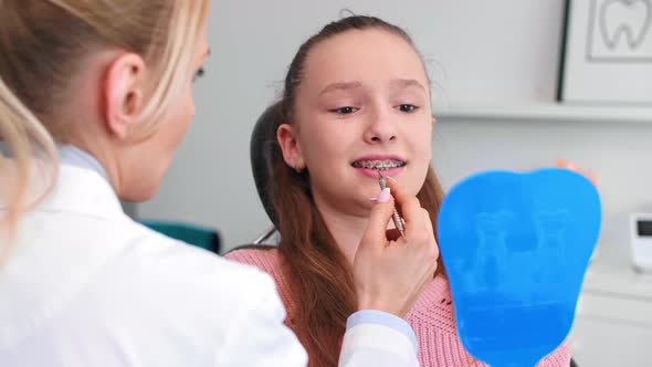 Female Orthodontist Examining Child's Teeth in Dentist's Office