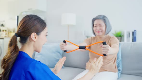 Asian Disabled old woman use resistance stretch doing physiotherapist with support from nurse.