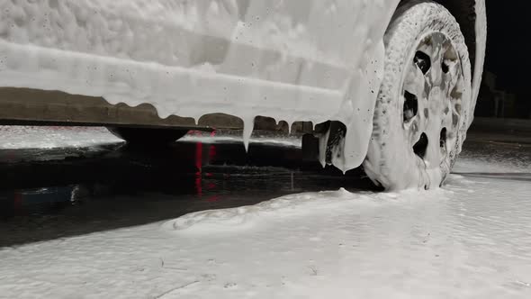 White Soap Sud Falling Down From Car Door During Car Wash Procedure at Night in Public Station