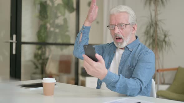 Senior Old Man Reacting to Loss on Smartphone in Office