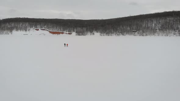 Aerial Shooting of a Two Guys Trekking Crossing Frozen River