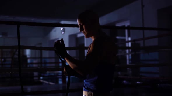 Tracking Shot of Motivated Bald Boxer Male Wrapping Black Boxing Tape Around Wrist Before Fight in