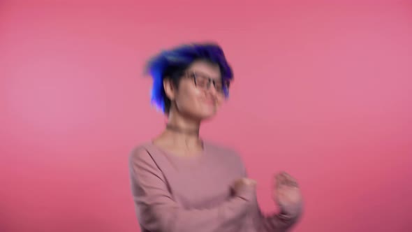 Beautiful Woman with Trendy Blue Hair Dancing on Colorful Pink Studio Background