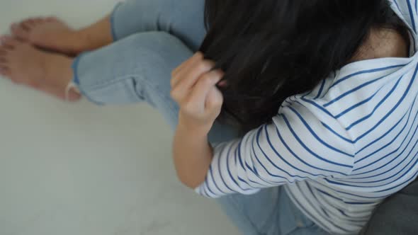 Close up of Asian young woman sitting on floor with lost hair in house.