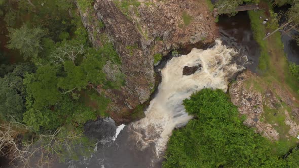 Birds eye view spinning aerial shot of a water fall in the East African jungle.