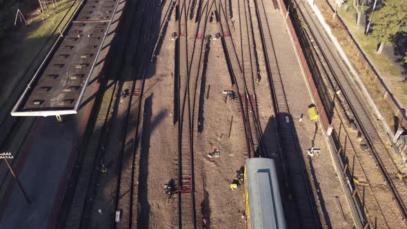 Aerial flight over train entering Federico Lacroze Station in Buenos Aires during summer - tilt up s