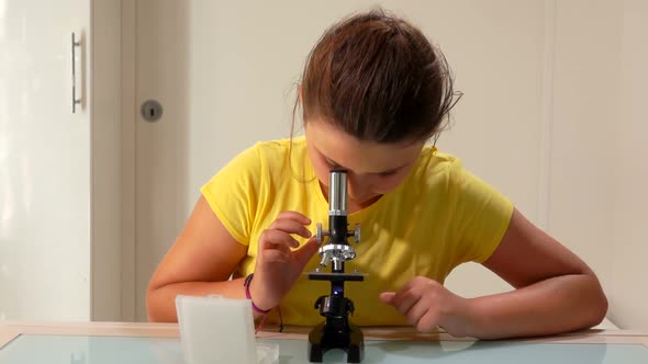 Serious Girl Changes a Sample in a Microscope