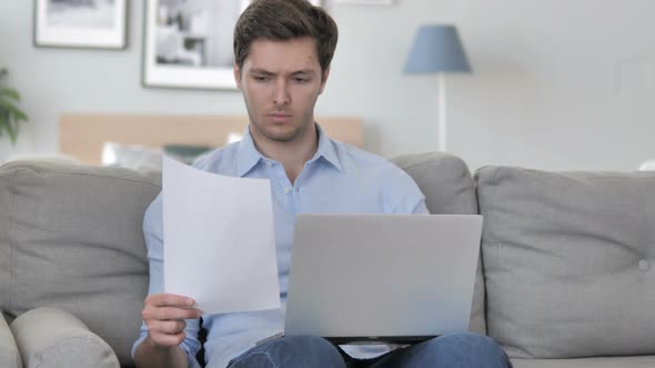 Young Man Doing Paperwork while Sitting in Creative Workspace