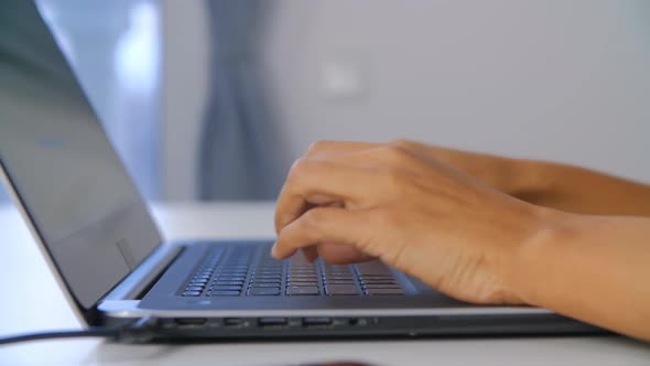 Hands of businesswoman working on notebook computer at home during lockdown