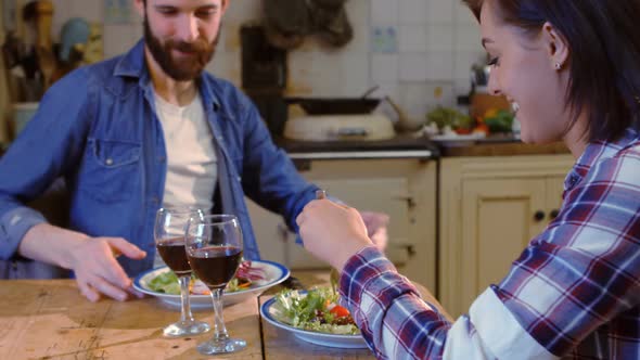 Young couple talking while having meal in kitchen