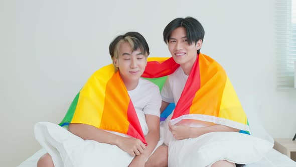 Portrait of Asian handsome man gay family holding LGBT flag and smile and looking at camera